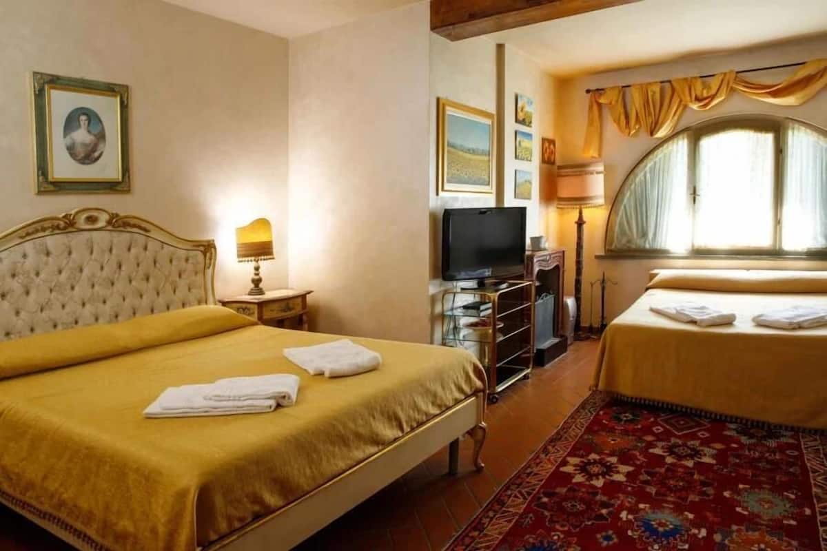 A hotel room with a large bed, a smaller bed, a television, and a window with curtains.