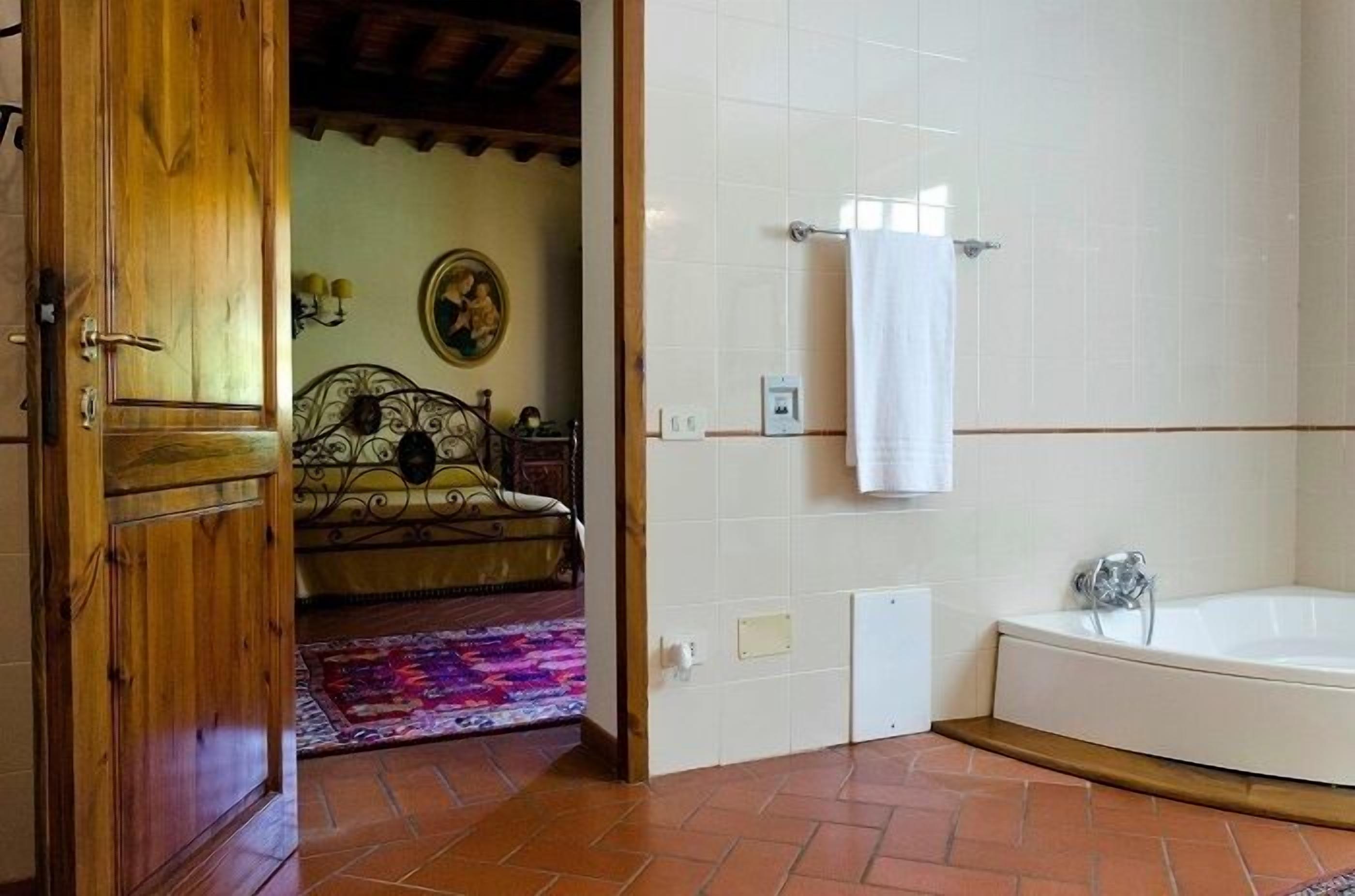 Un baño con bañera, puerta de madera y pared de azulejos.
