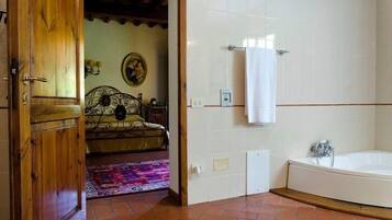 Un baño con bañera, puerta de madera y pared de azulejos.