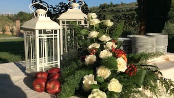 Taula amb llums blanques, roses blanques, pomes vermelles i fullatge verd.