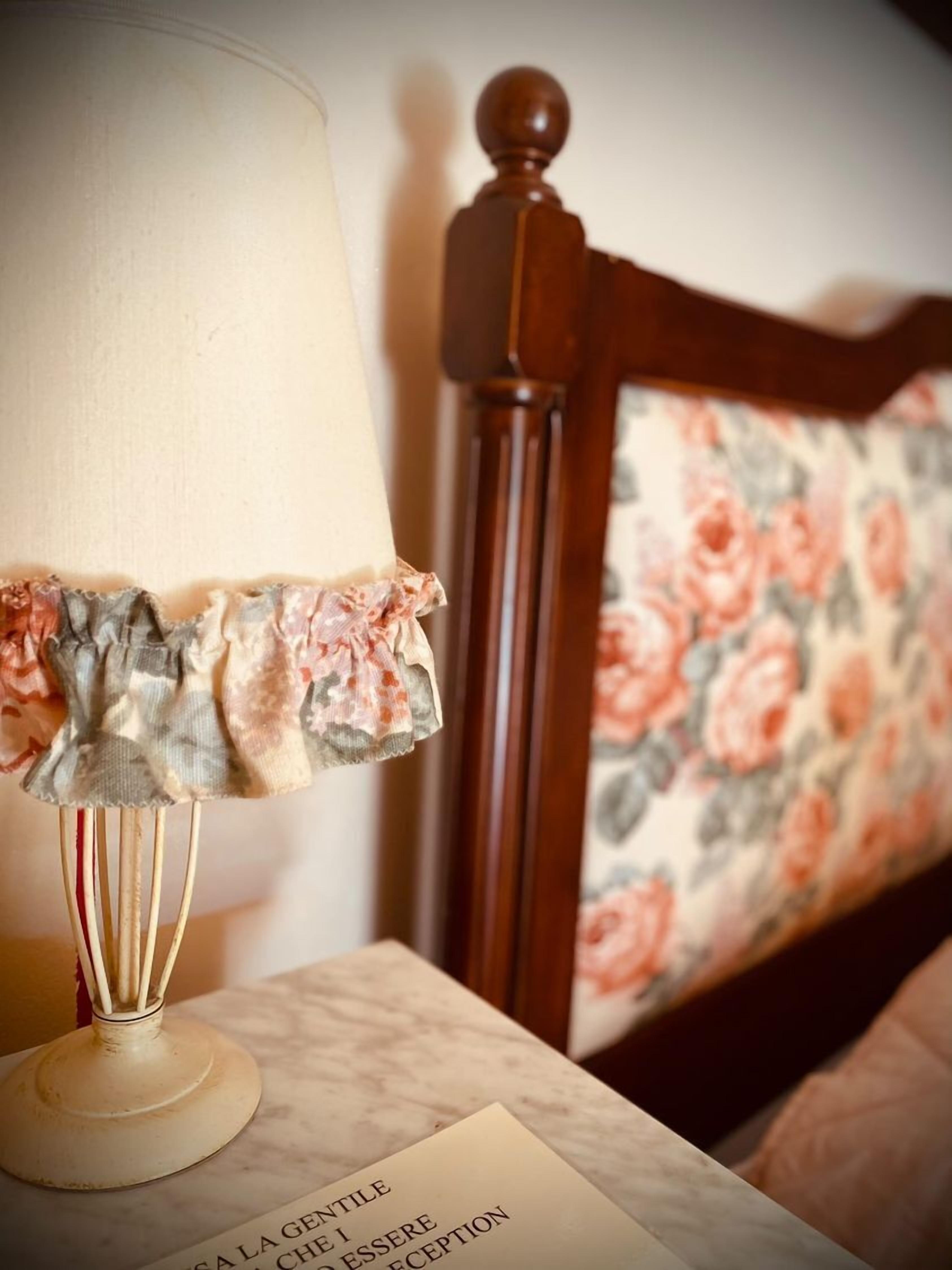 Een bed met een bloemenkussen en een nachtkastje met een lamp.