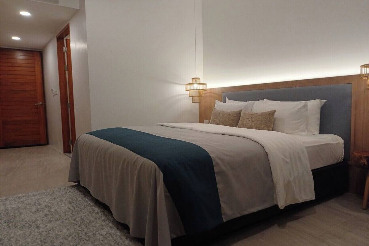 A neatly arranged bedroom with a bed, bedside tables, and a carpeted floor.