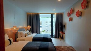 A hotel room with two beds, a large window, and a view of a building outside. - Mukrada House (Krabi)