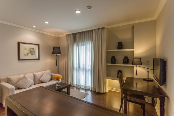 A modern living room with a sofa, coffee table, TV, and shelves.