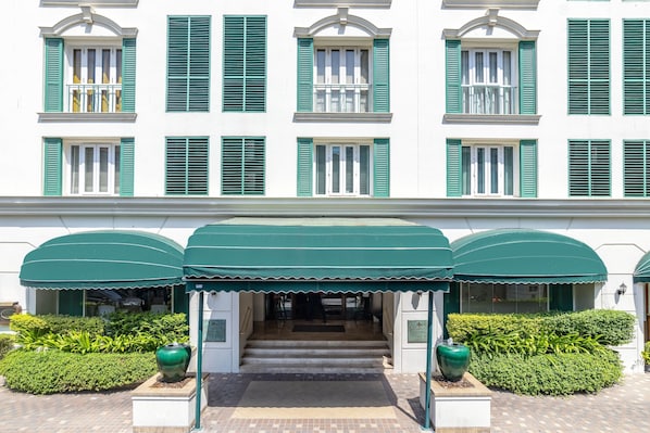 Un bâtiment avec des volets verts et une entrée abritée.