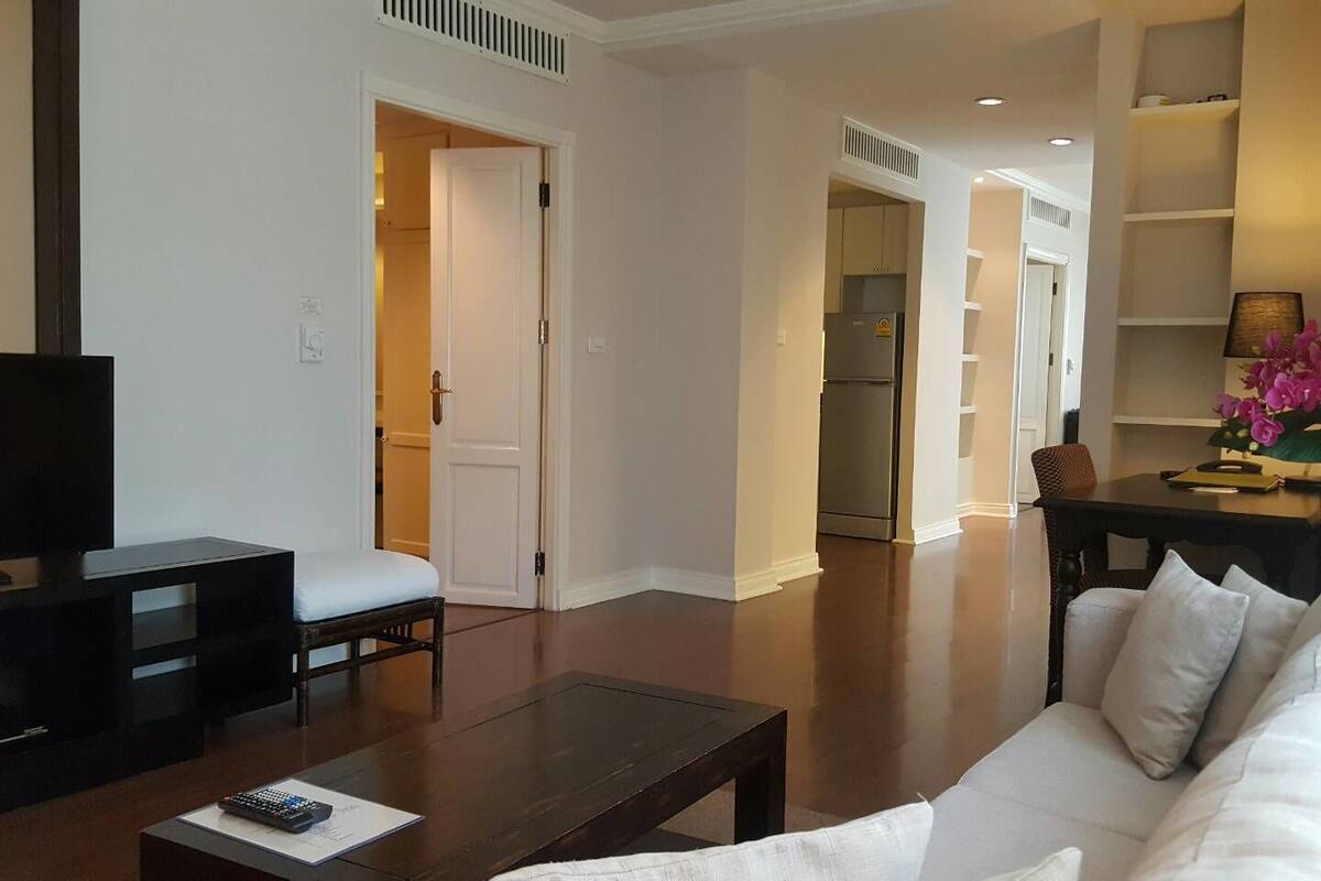A living room with a sofa, coffee table, TV, and a dining area with a table and chairs.