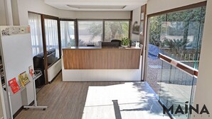 A reception area with a wooden desk, a sofa, and a refrigerator. - Presto Hotel (Blumenau)