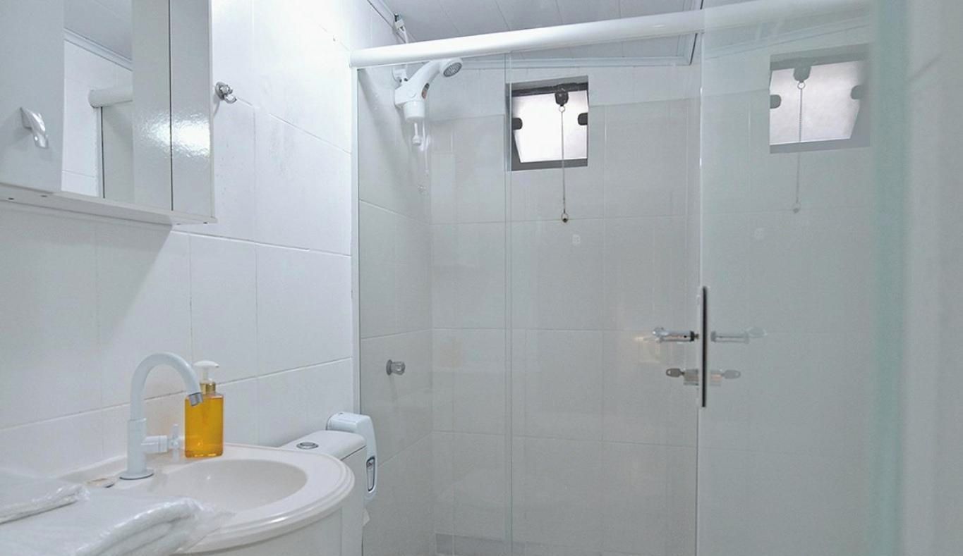 Une salle de bain avec un lavabo blanc, un miroir et un espace douche.