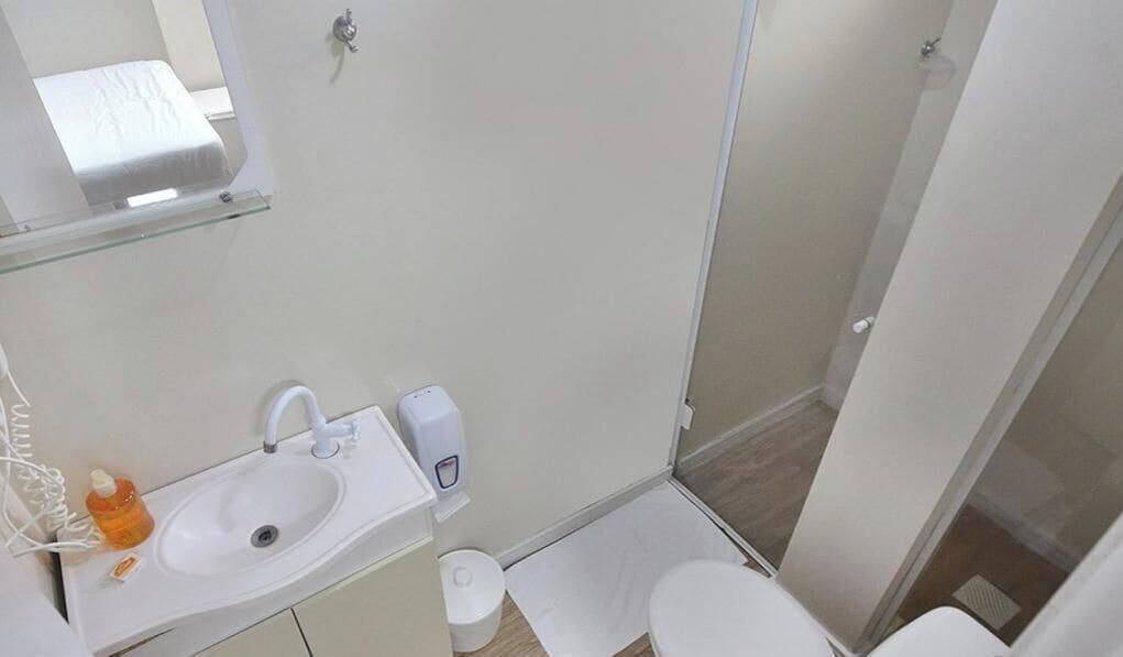 Un baño pequeño con un lavabo blanco, un espejo, un inodoro y una zona de ducha.