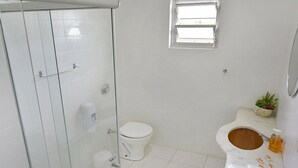 A bathroom with a glass shower enclosure, a toilet, and a bidet. - Presto Hotel (Blumenau)