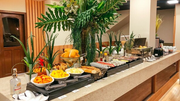 A buffet with various food items and a bottle of alcohol. - Presto Hotel (Blumenau)