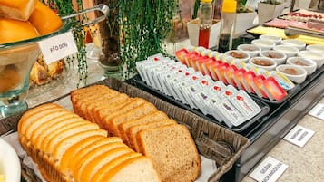 Un bufé con diferentes opciones de comida, incluyendo pan en rebanadas, queso y salsas.