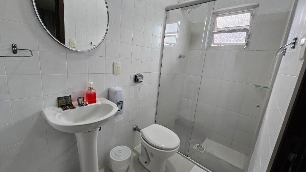 A bathroom with a white sink, toilet, and a glass-enclosed shower.