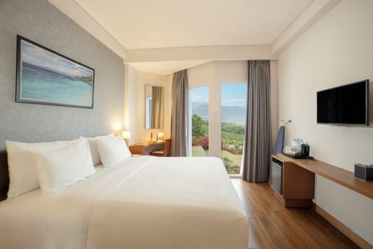 Une chambre d’hôtel avec un grand lit, un bureau, une télévision et une vue panoramique.