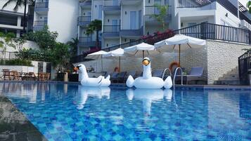 Una piscina con flotadores inflables con forma de cisne y sillas de descanso.