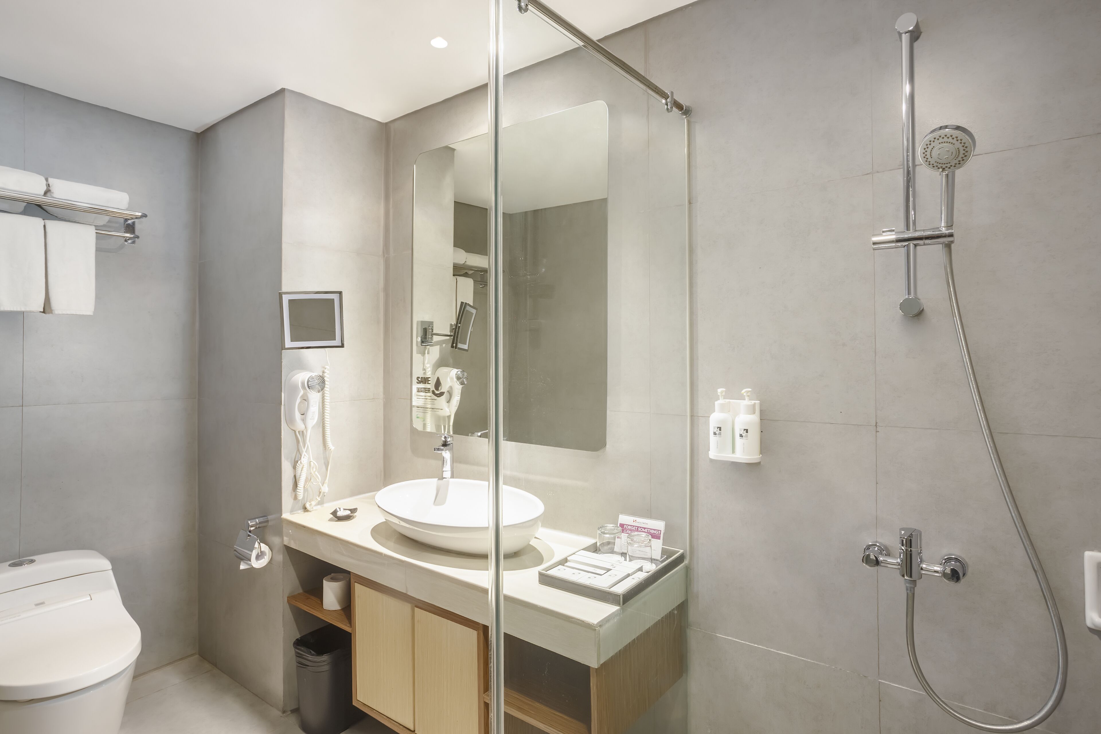 A modern bathroom with a glass shower enclosure, a white sink, and a toilet.