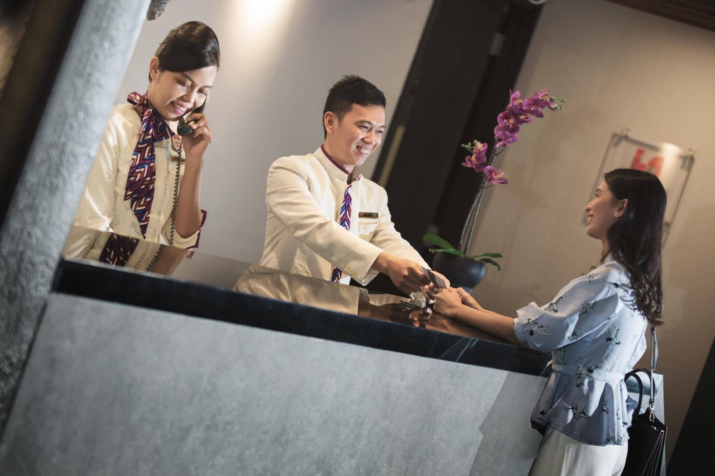 A reception area with a counter, a plant, and a sign in the background.