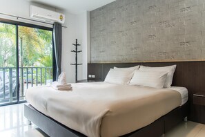 Habitación de hotel con una cama grande, vistas al exterior y una pared con diseño de ladrillo.