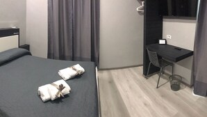 Habitación de hotel con cama, escritorio, silla y televisor.