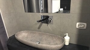 Un baño moderno con lavamanos de piedra, encimera negra y espejo.