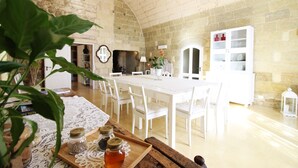 A dining area with a white table and chairs, a wooden bench with jars, and a stone wall. - Don Agostino Relais Masseria (Martano)