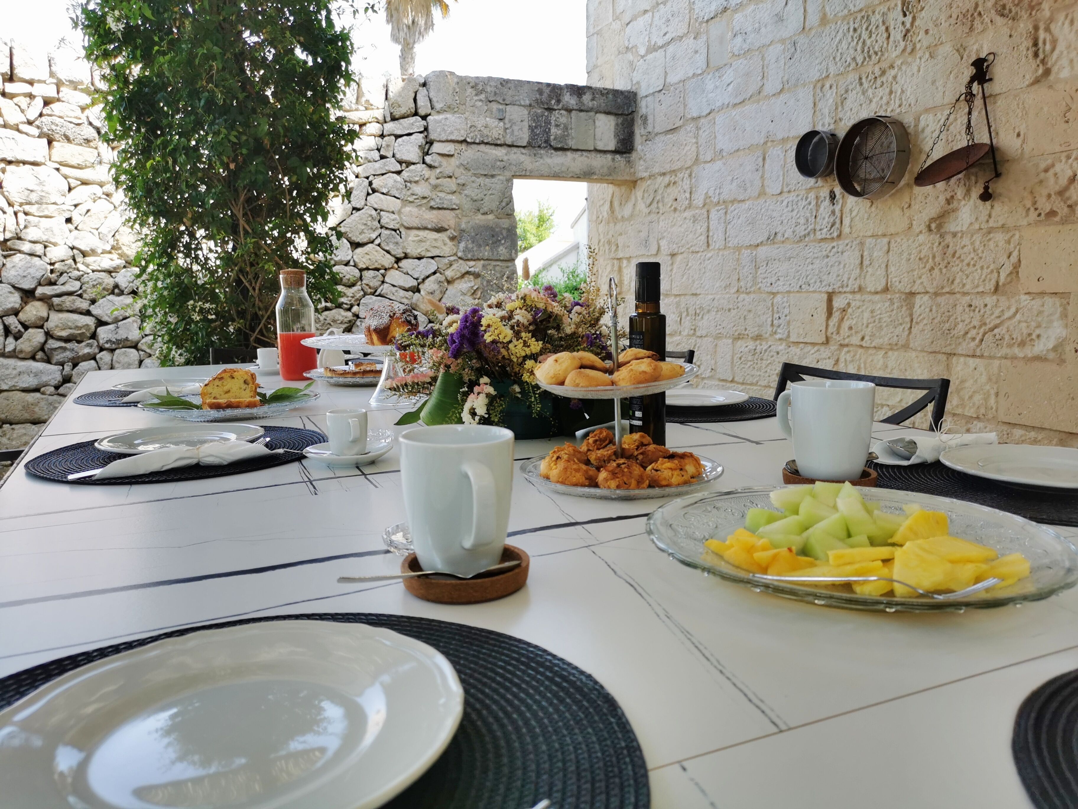 Una mesa lista para el desayuno, con platos, tazas y diversos alimentos.