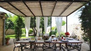 An outdoor patio with a covered dining table set for four, surrounded by chairs. - Don Agostino Relais Masseria (Martano)