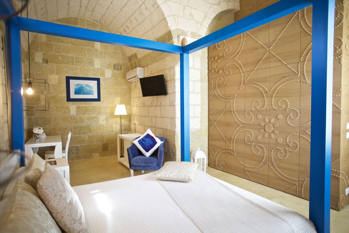 Ein Hotelzimmer mit Bett, Schreibtisch, Stuhl und Fernseher an der Wand.