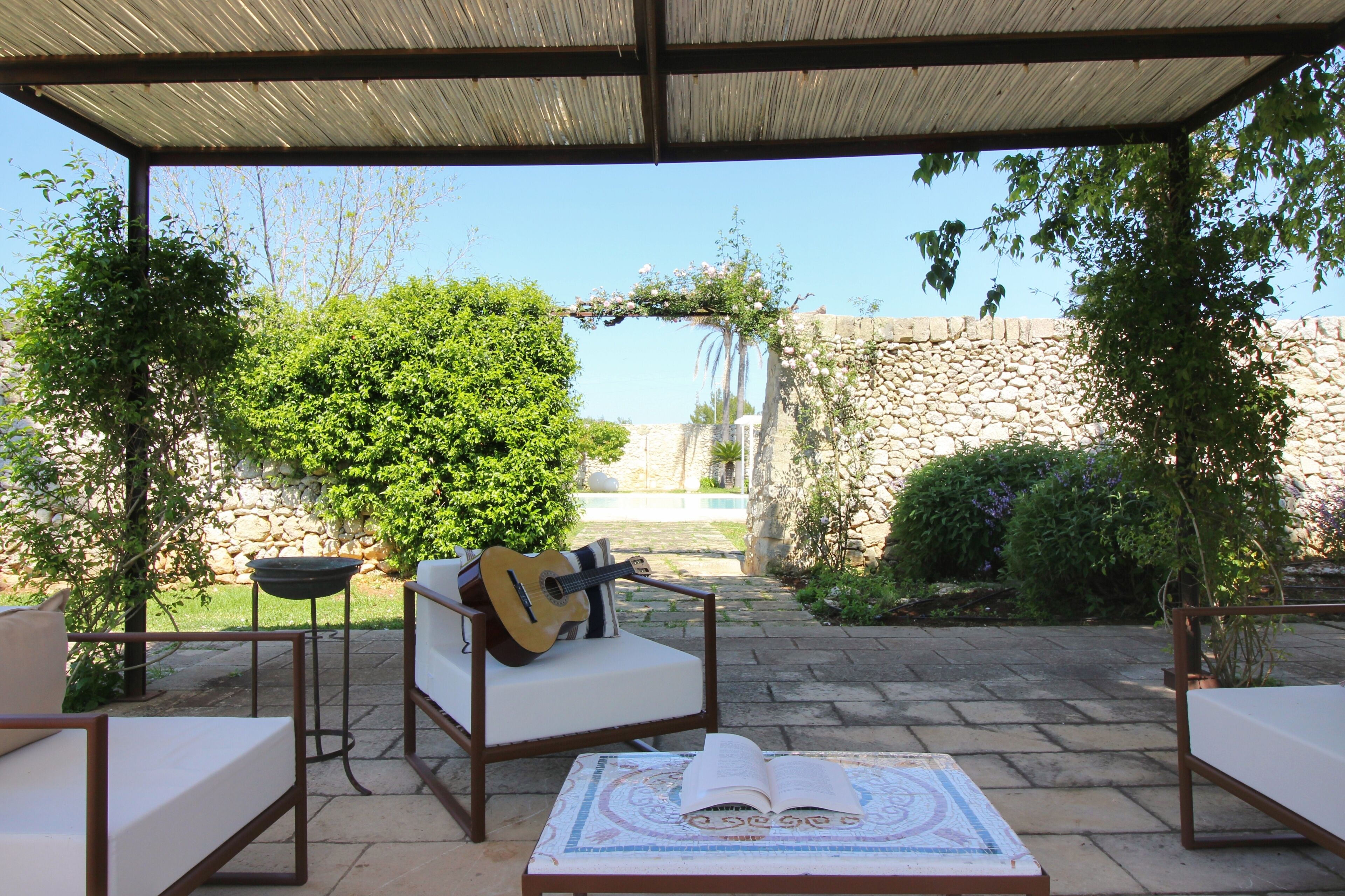 An outdoor patio with a covered seating area, a guitar, and an open book on a table.