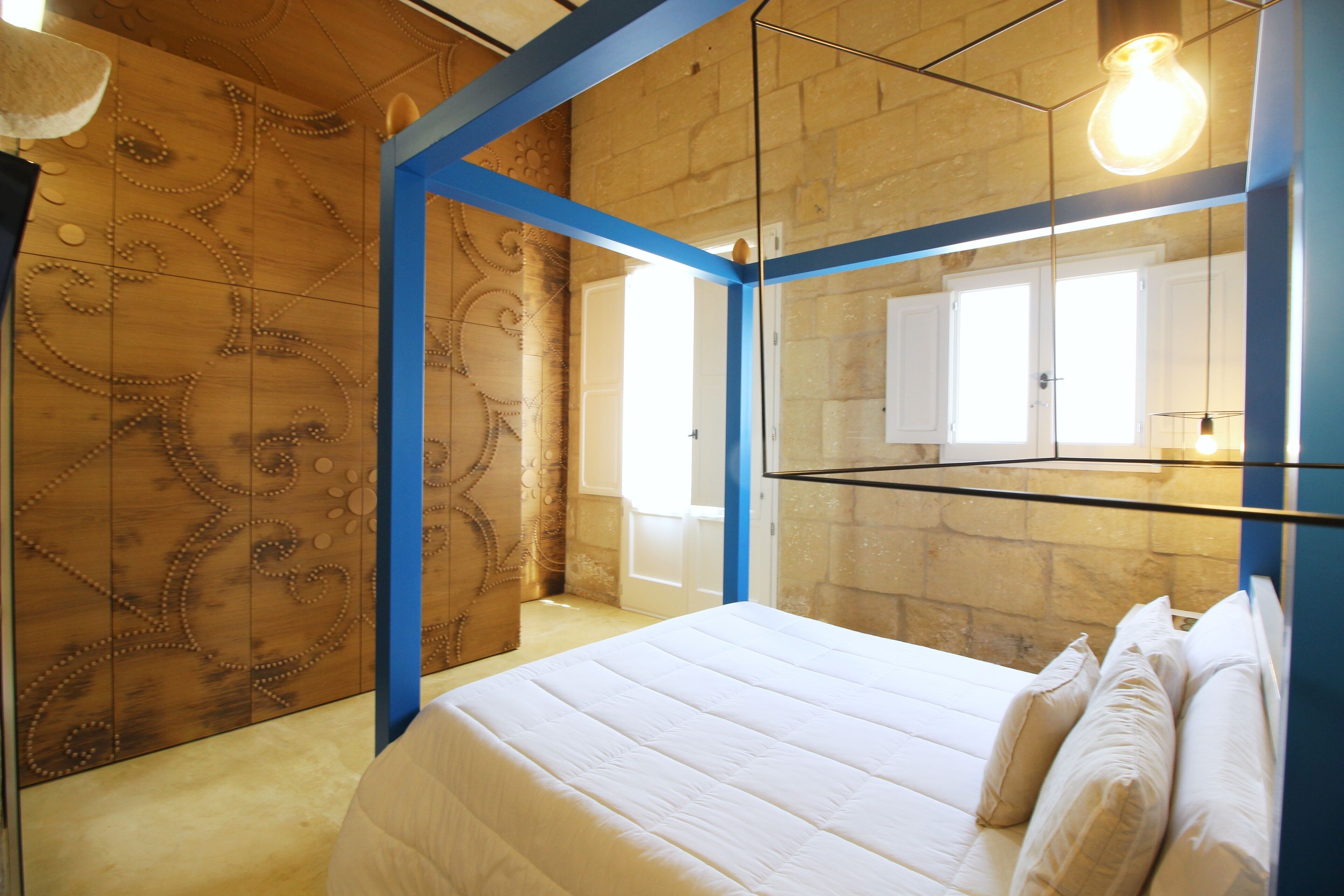 A bedroom with a bed, a mirror, and a decorative wall.