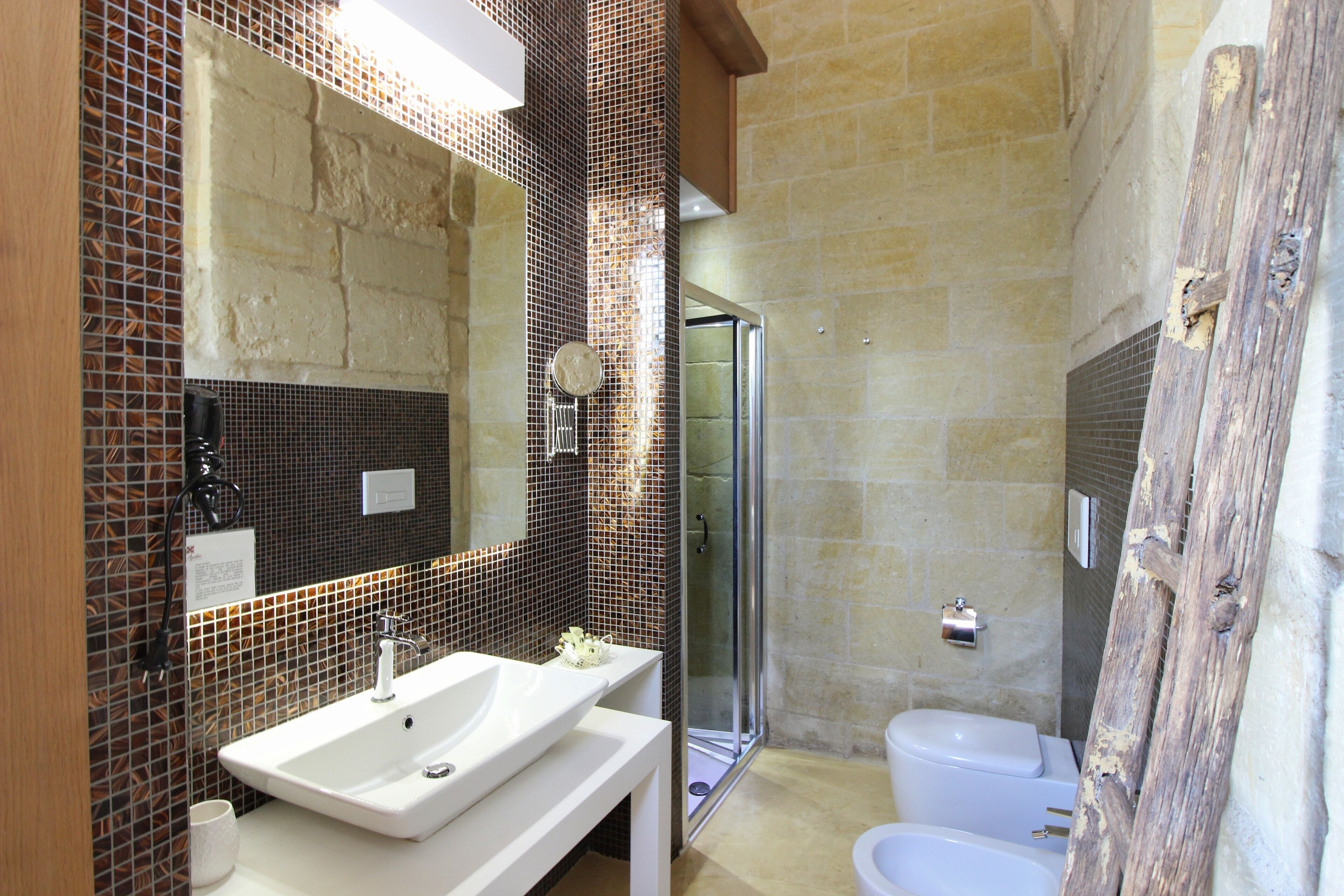 A bathroom with a white sink, a mirror, a shower, and a toilet.