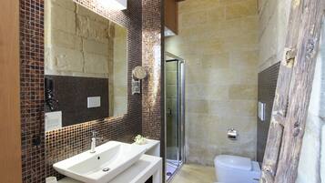 A bathroom with a white sink, a mirror, a shower, and a toilet.