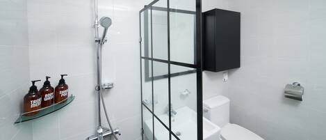 Un baño moderno con cabina de ducha de vidrio, inodoro blanco y botiquín negro.