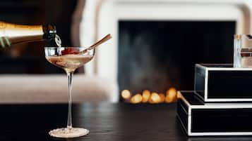 A martini glass on a table with a bottle of champagne being poured into it.