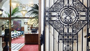 A hotel entrance with a decorative wrought iron gate, a checkered floor, and a view of the interior dining area with tables and chairs. - Bank Hotel, a member of Small Luxury Hotels of The World (Stockholm)
