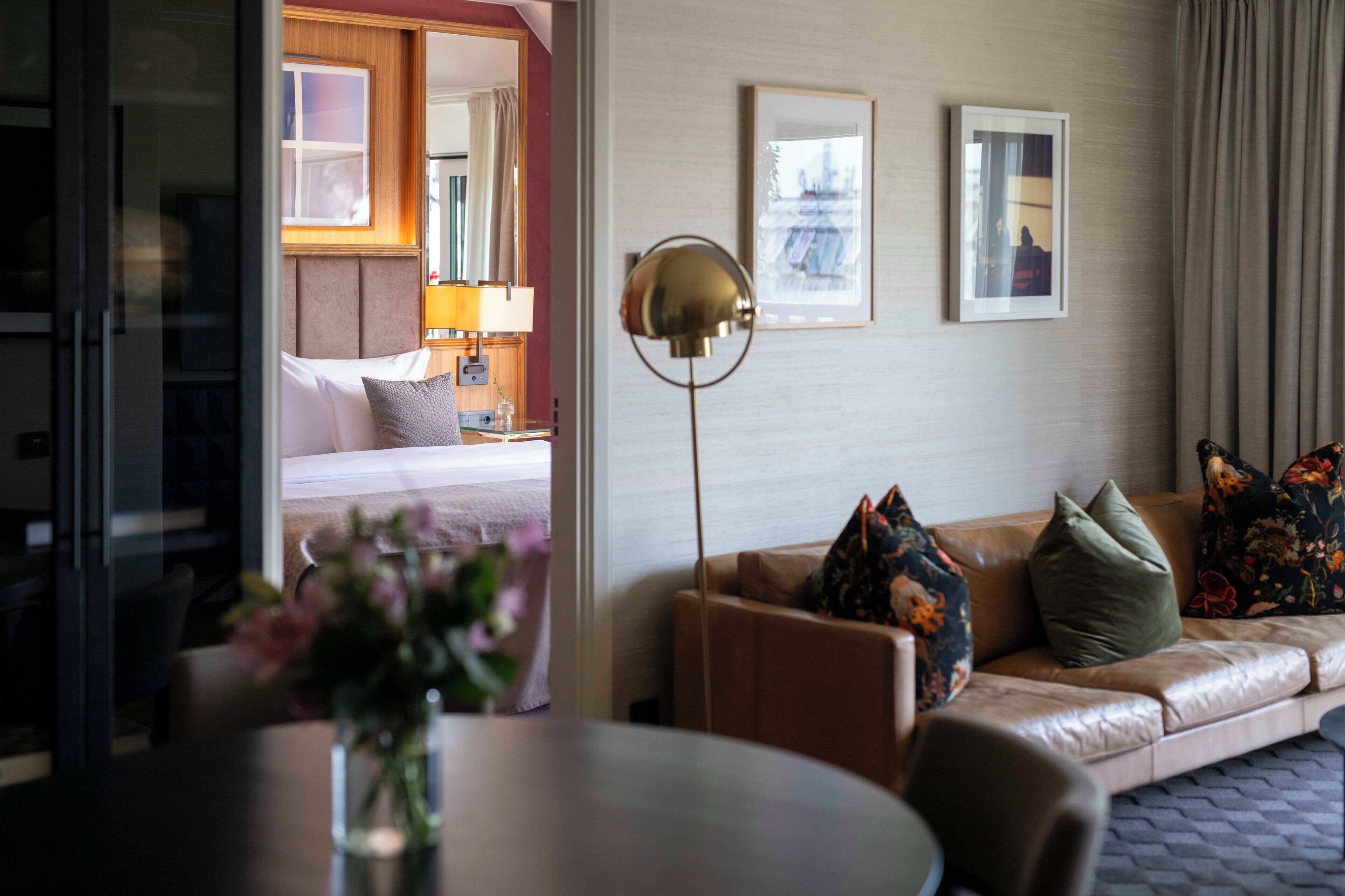 Una habitación de hotel con cama, sofá, lámpara de pie y mesa de comedor.