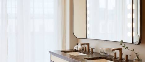 Baño con dos lavamanos, un espejo grande y luces en el tocador.
