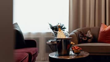 A living room with a red sofa, a round coffee table with a fruit bowl and a champagne bucket.