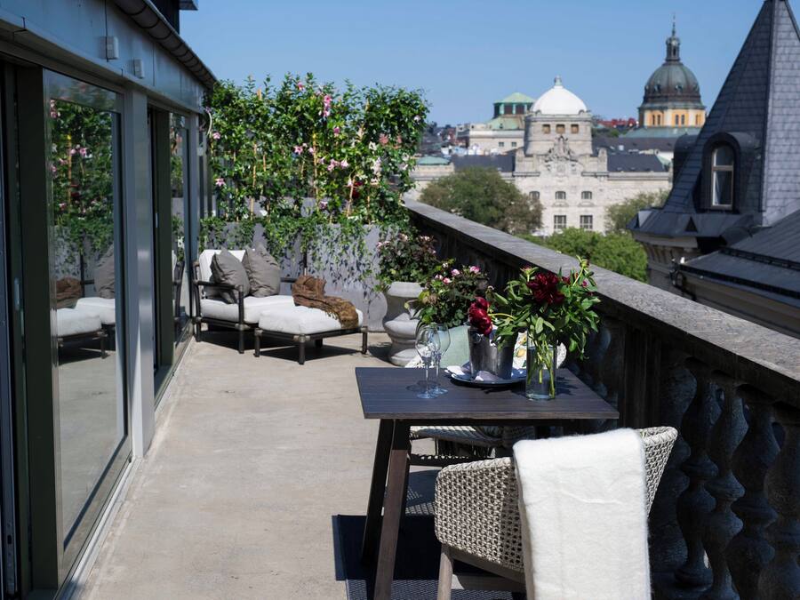 A balcony with a table, chairs, and a view of historic buildings.