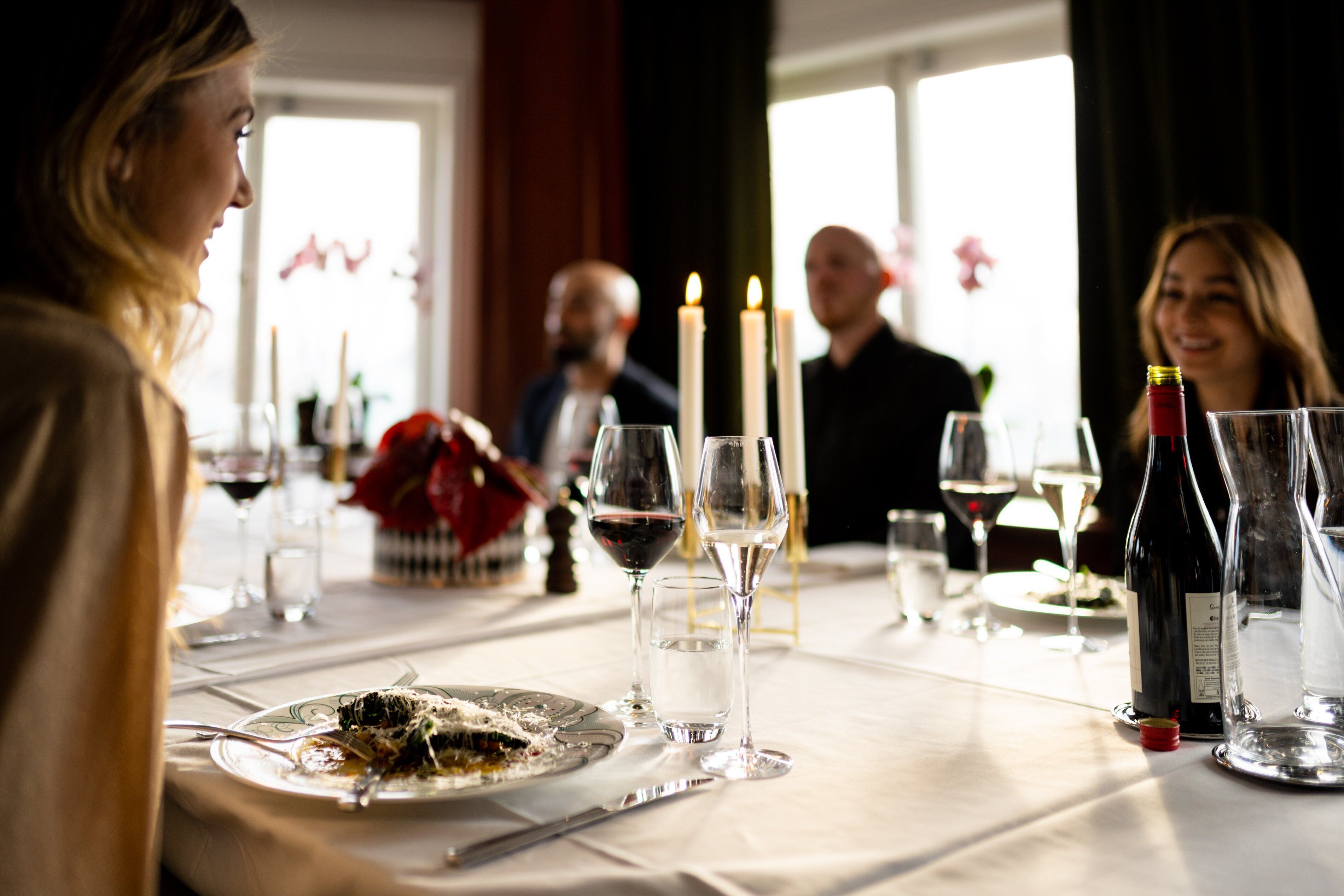 A dining table set with plates, cutlery, glasses, and candles, suggesting a formal dining setting.