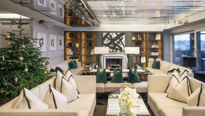 A modern living room with a fireplace, sofas, a coffee table, and a Christmas tree. - Bank Hotel, a member of Small Luxury Hotels of The World (Stockholm)