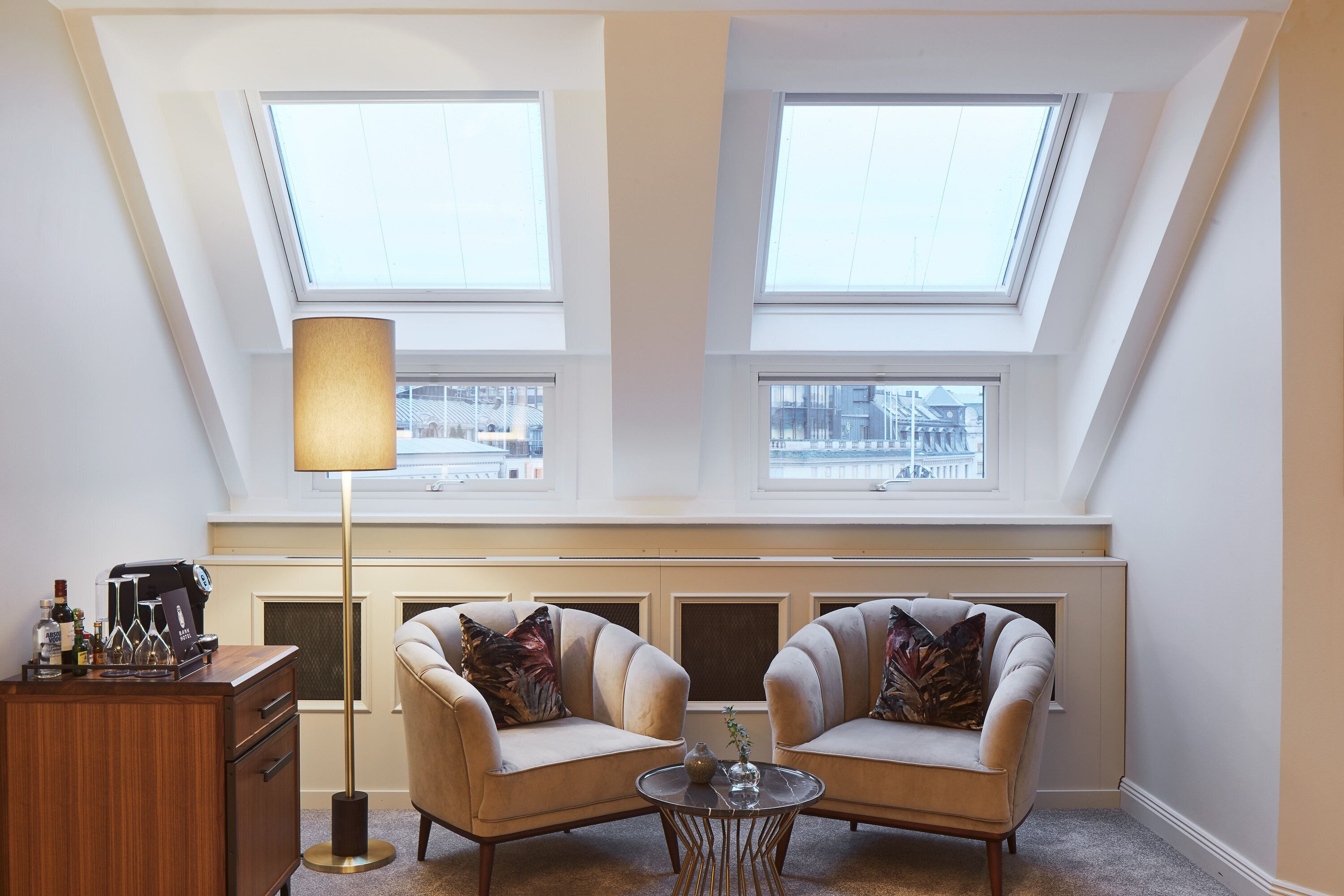 A room with two armchairs, a coffee machine, a lamp, and a view through skylights.