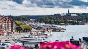 A riverside view with a large white boat docked at a pier, surrounded by buildings and greenery. - Bank Hotel, a member of Small Luxury Hotels of The World (Stockholm)