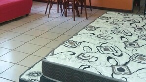 A room with a bed, a red sofa, a dining table with chairs, and a ceiling fan. - Residencial Salinas (Florianópolis)
