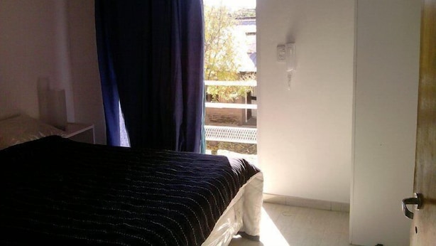 Un dormitorio con una cama, una ventana con cortinas y una puerta.