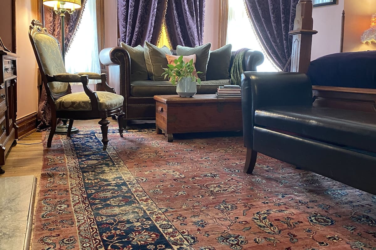 A traditional living room with a patterned rug, a sofa, a chair, and a lamp.