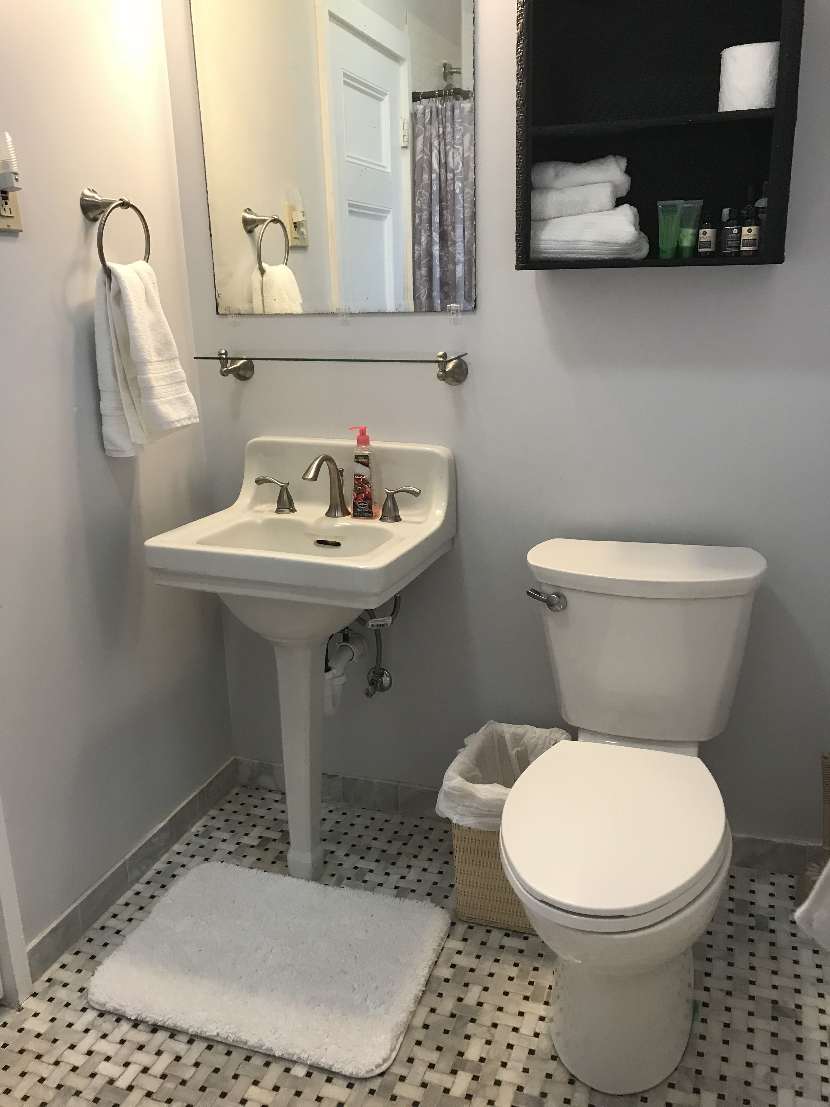 Baño con lavamanos, inodoro y espejo.
