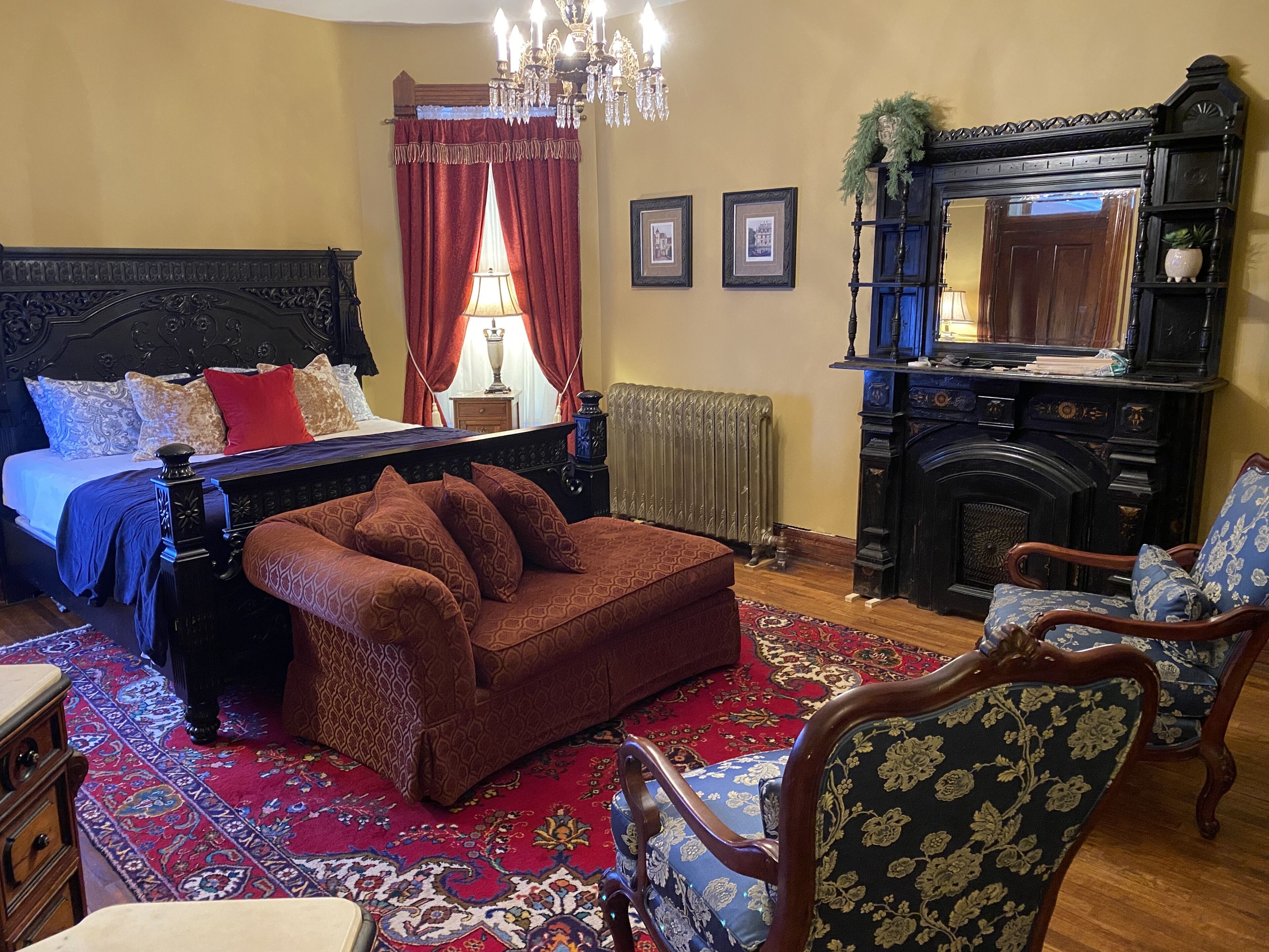 A traditional bedroom with a four-poster bed, a red sofa, and a fireplace.