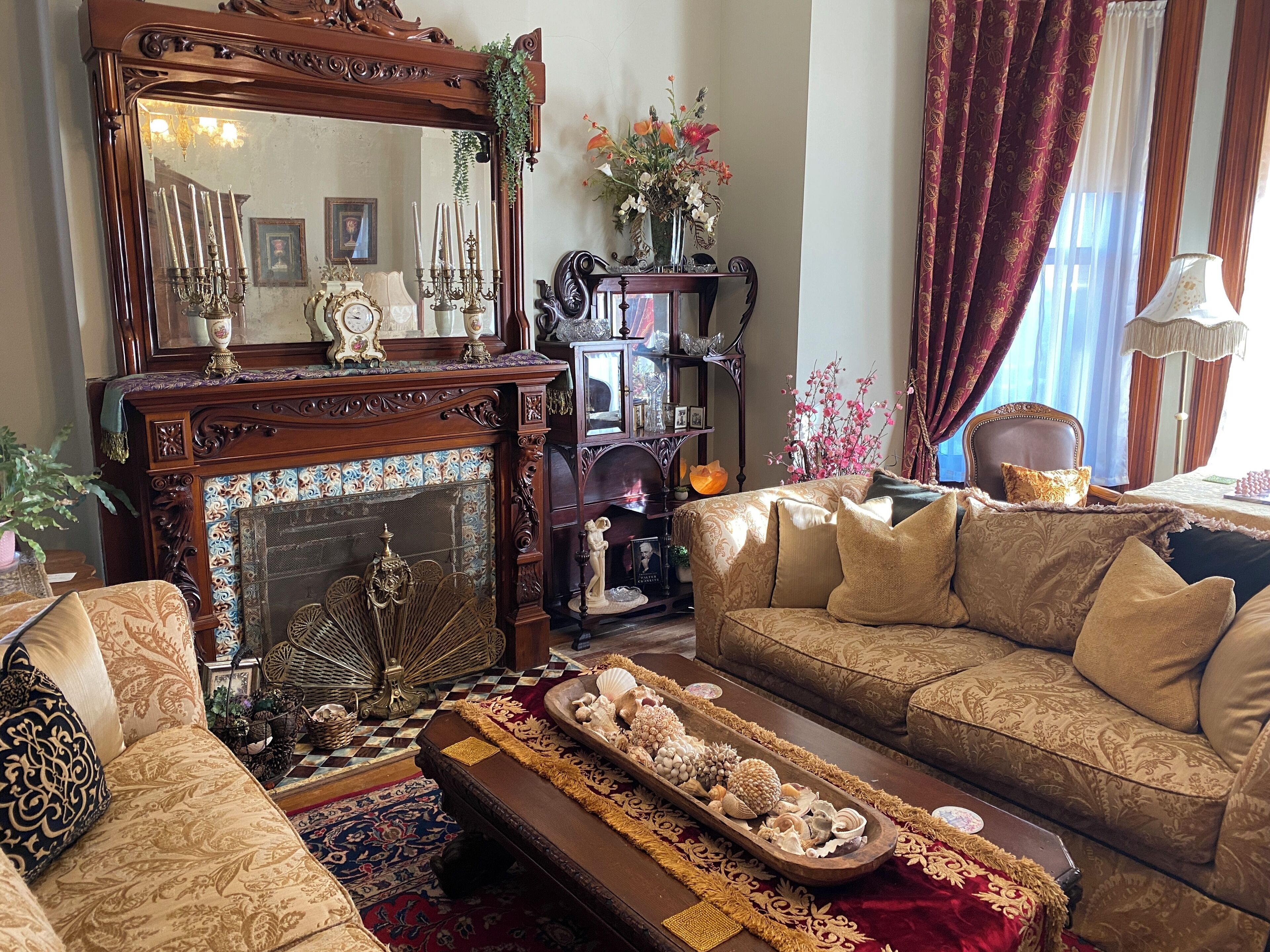 A traditional living room with a fireplace, ornate furniture, and a large mirror.