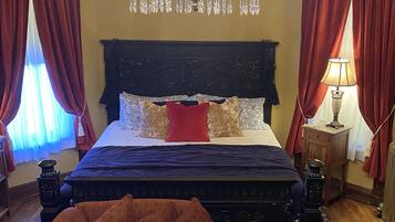 Una camera da letto con un letto grande, un lampadario, tende rosse e un divano decorato.